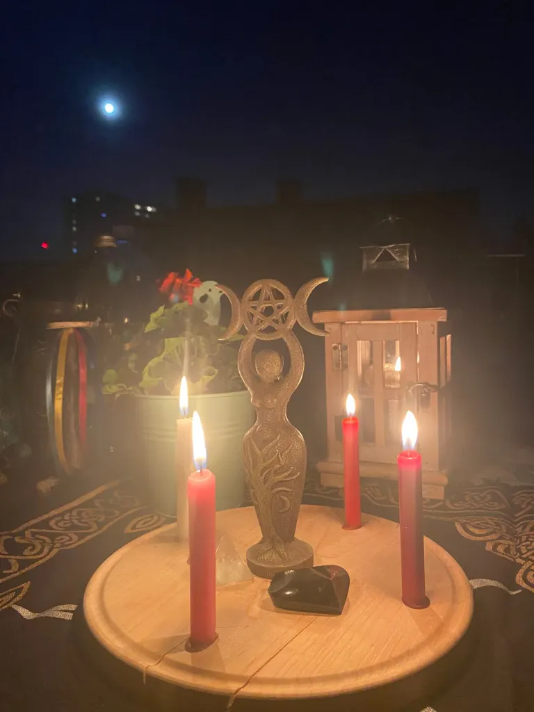 Vollmondaltar bei Nacht mit roten Kerzen und Jahreskreis-Symbolen